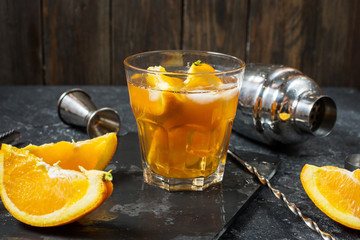 A glass of Negroni cocktail with orange and lemon. Alcoholic drink with rum and vermouth on dark stone table