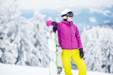 Portrait of a young woman snowboarder standing outdoors on the snowy mountains