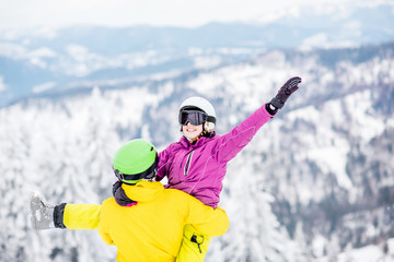 Young couple in snowboarding clothes having fun during the winter vacation on the snowy mountains