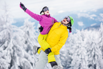 Fototapeta na wymiar Young couple in snowboarding clothes having fun during the winter vacation on the snowy mountains