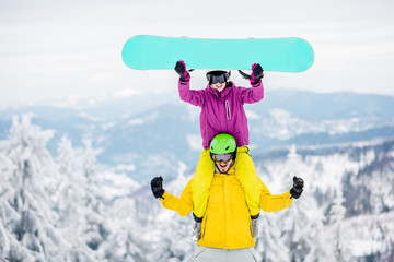 Young couple in snowboarding clothes having fun during the winter vacation on the snowy mountains