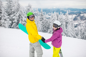 Fototapeta na wymiar Young couple walking with snowboards during the winter vacation on the snowy mountains