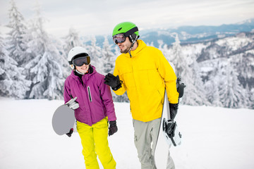 Fototapeta na wymiar Young couple walking with snowboards during the winter vacation on the snowy mountains