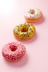 Donuts selection on pink pastel background. Various doughnuts isolated on colorful background