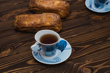 Puff pastry with a cup of tea on a wooden background.