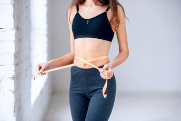 Concept of healthy eating, diet, nutrition. Young girl in black sportswear with perfect waist...