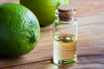 A bottle of lime essential oil with fresh limes in the background