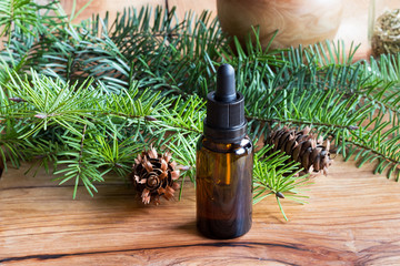 A bottle of Douglas fir essential oil with Douglas fir branches and cones