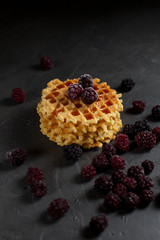 round fresh waffles with caramel and blackberry berries on a dark background