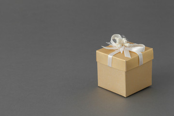 Gift box with ribbon on gray background, copy space for text.