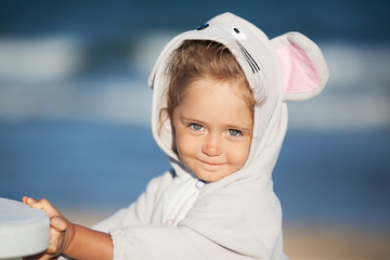 Little girl in a mouse costume on the beach