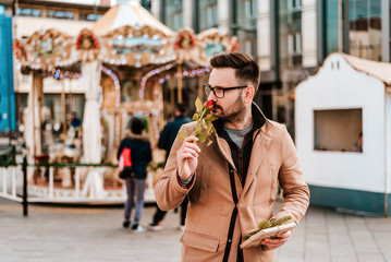 Handsome romantic happy man holding and smelling rose.