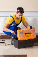 Young repairman contractor repairing heating panel 