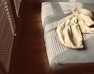 Obraz na płótnie Canvas Wooden blinds in a home and blanket on the bed catching the sunlight with burst light in the morning
