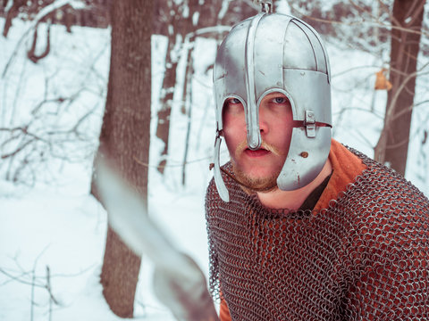 Medieval Irish warrior in chain mail and helmet holds a spear in the winter forest