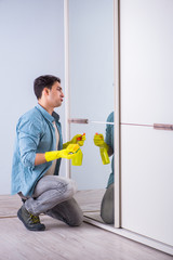 Young man cleaning mirror at home hotel