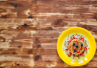 Homemade pancakes with fresh berries, strawberries, blueberries and maple syrup on a wooden background.