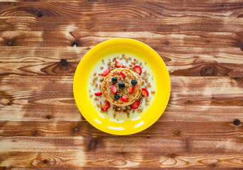 Homemade pancakes with fresh berries, strawberries, blueberries and maple syrup on a wooden background.