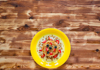 Homemade pancakes with fresh berries, strawberries, blueberries and maple syrup on a wooden background.