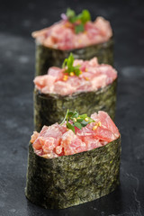 Three Gunkan maki sushi with tuna on black background