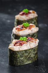 Three Gunkan maki sushi with scalop meat and sauce spice on black background