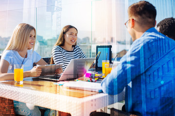 Positive day. Delighted group of students expressing cheer while sitting in the cafe and communicating