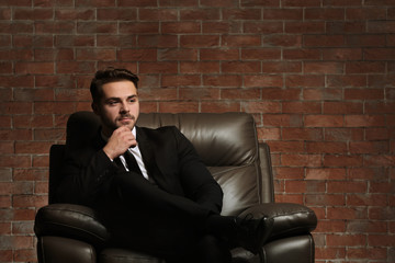 Man in elegant suit on brick wall background