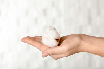 Woman holding cotton flower on light background