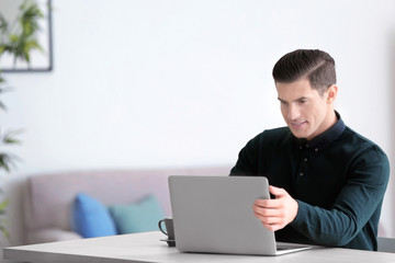 Young man using laptop at table indoors