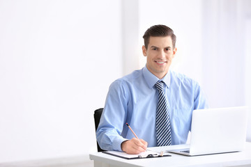 Young man in office wear using laptop indoors