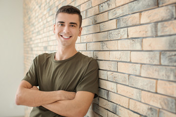 Portrait of young man in casual clothes near brick wall
