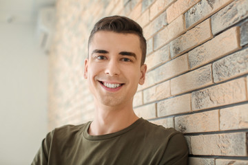 Portrait of young man in casual clothes near brick wall