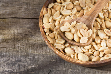 Toasted peanuts on wooden background - Arachis hypogaea