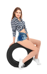 Fototapeta na wymiar Young woman in seductive outfit with car tire on white background
