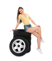 Fototapeta na wymiar Young woman in seductive outfit with car tires on white background