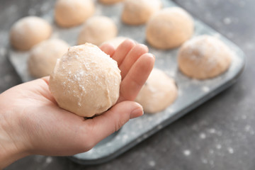 Woman holding ball of raw dough, closeup