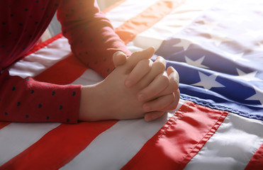 Little girl praying over American flag, closeup
