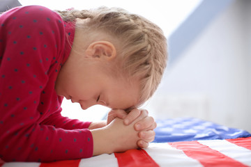 Cute little girl praying over American flag © Africa Studio