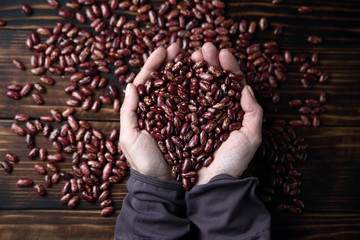 женщина держит в руках горсть красной фасоли