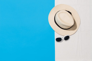 Top view of sandy beach with towel frame and summer accessories. Punchy pastels colors graphical background with copy space. Right border made of towel