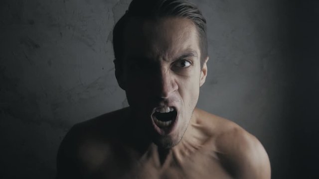 Angry and dangerous man in a dark room. Emotion of the evil man. Mouth of Angry Man screaming. Danger Violence