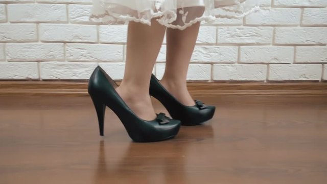 A child in women's shoes. Little girl in high heels.