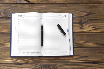 Diary, pen, against the background of a wooden table. planning.