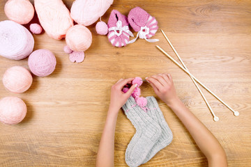 Obraz na płótnie Canvas Woman female girl knits a new warm socks on wooden background. Dressmaker workplace. Top view