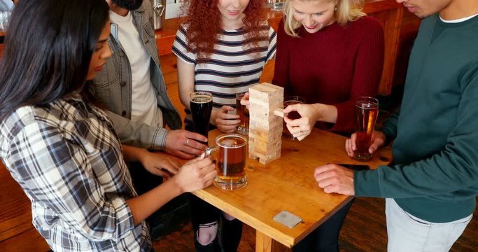 Group of fiends playing jenga while having beer 