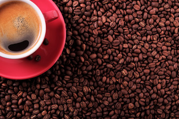 Red coffee cup and saucer one single for espresso or capuccino on a background of scattered dark coffee beans photo