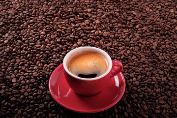 Red coffee cup and saucer one single for espresso or capuccino on a background of scattered dark coffee beans photo