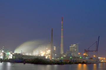 Long time exposure of an industrial plant located on river Weser bank at night with large chimneys,...