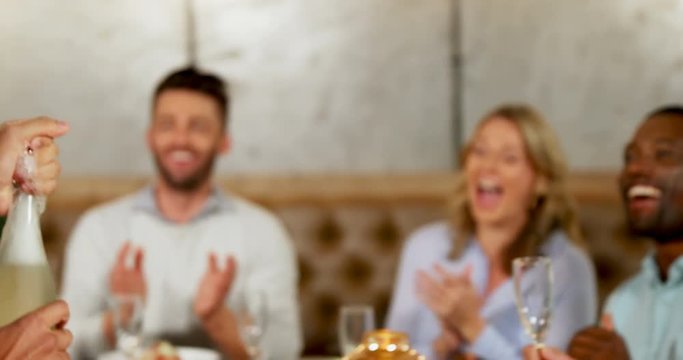 Man serving champagne to his friends on dinner table  