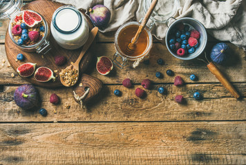 Fototapeta na wymiar Healthy vegan breakfast. Oatmeal granola with bottled almond milk, honey, fresh fruit and berries over rustic wooden table background, copy space, top view. Clean eating, weight loss food concept
